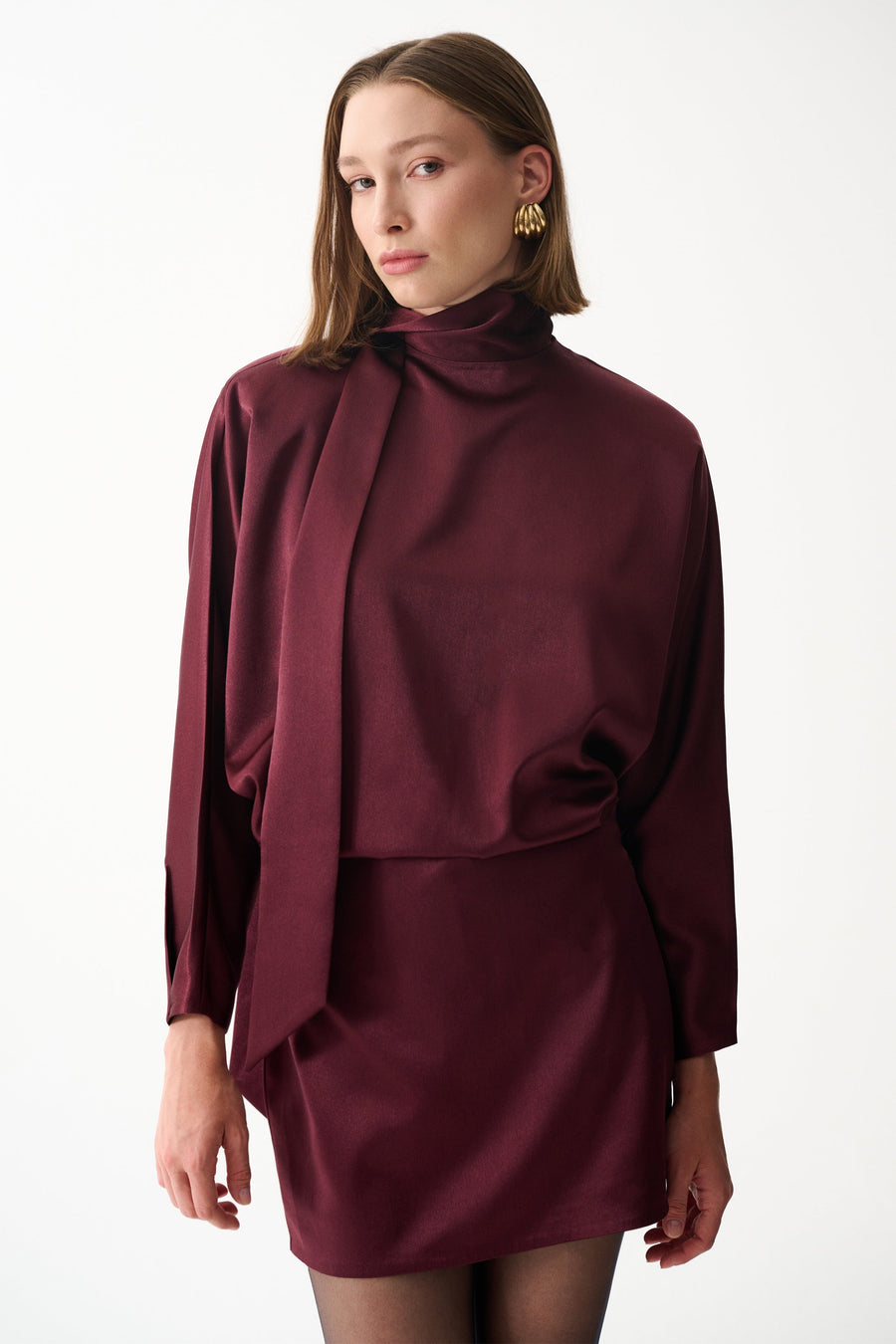 Burgundy satin mini dress with long sleeves, high neck, and draped scarf detail