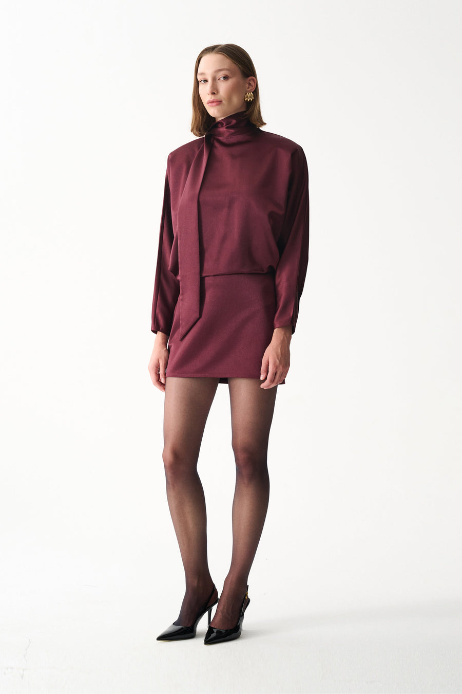 Burgundy satin mini dress with long sleeves, high neck, and draped scarf detail